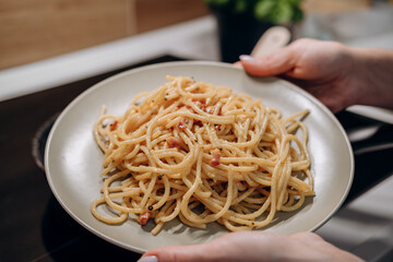 Step by step the process of cooking Italian pasta carbonara in spaghetti, add sauce with fried cubes of pancetta or bacon, eggs, cheese and garnish with basil