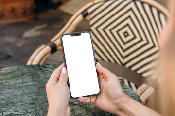Mockup woman's hand holding using smart phone with white blank screen POV at coffee shop, mobile app design and advertising, online marketing