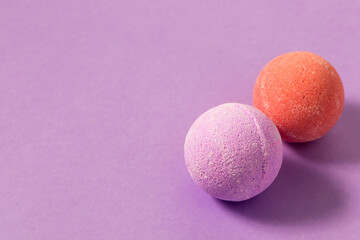 Colorful bath bombs placed on a light purple surface during a relaxing spa moment