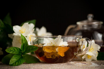 Soothing tea with jasmine flowers on a black background