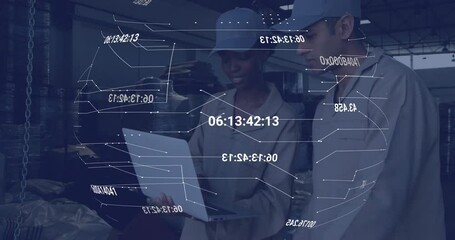 Two warehouse technicians unfolding laptop and navigating live data overlay for stock management - Powered by Adobe