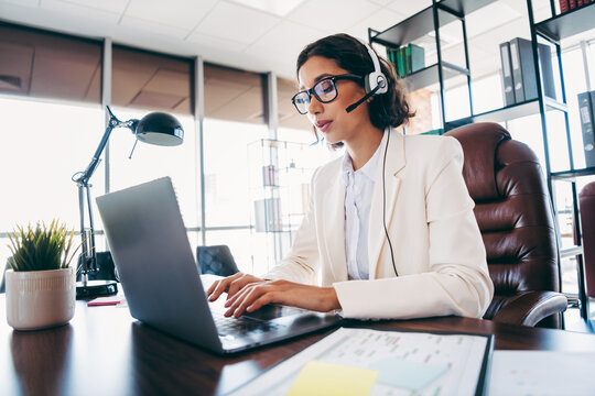 Professional businesswoman wearing a headset while working at her desk in a modern office setting