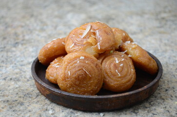 Traditional Indian sweet balushahi – deep-fried flaky dough dessert soaked in sugar syrup, golden and crispy, often garnished with dry fruits – festive mithai served on plate