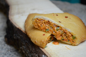 Crispy baked pizza pocket – golden brown stuffed pastry filled with cheese, vegetables, and pizza sauce served hot as snack or appetizer, popular fusion fast food