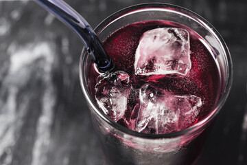 Cold berry juice with ice. Fizzy purple drink in glass with transparent cubes. Refreshing summer...