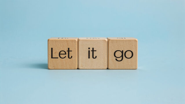 The phrase 'Let it go' spelled out on wooden letter cubes against a solid blue background. A motivational concept for mental health, forgiveness, and overcoming challenges.