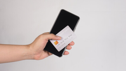 A hand holding a silver credit card and a smartphone ON white Background.
