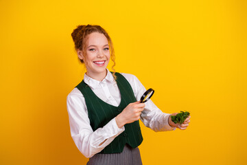Teenage girl exploring nature with magnifying glass against yellow background showcasing learning...