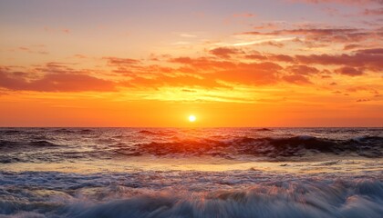 Fototapeta premium a stunning sunset paints the ocean waves in vibrant hues of orange and yellow creating a serene atmosphere ideal for nature lovers and photography enthusiasts