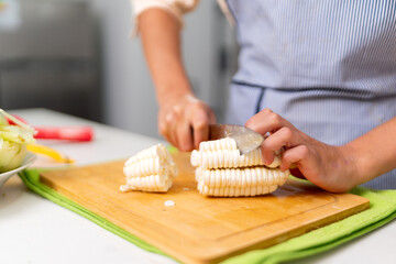 Chef cutting peruvian white corn, choclo, for ceviche preparation