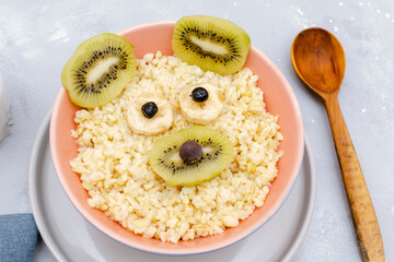 Funny cute kids childrens baby's healthy breakfast lunch oatmeal porridge in bowl like bear,mouse face with kiwi, banana, dried berry fruits. dessert food art