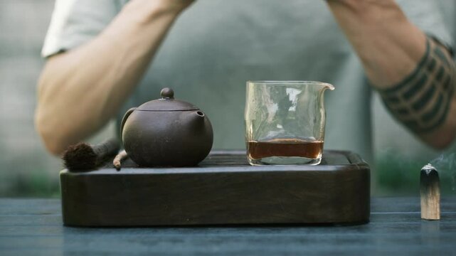 Chinese tea ritual in backyard as man enjoys energizing pu erh with full presence