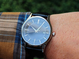 Man Wearing Elegant Wristwatch Outdoors. Man’s wrist wearing a sophisticated analog watch with a...