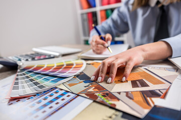 female hand making project with sketch plan blueprint and color palette at office