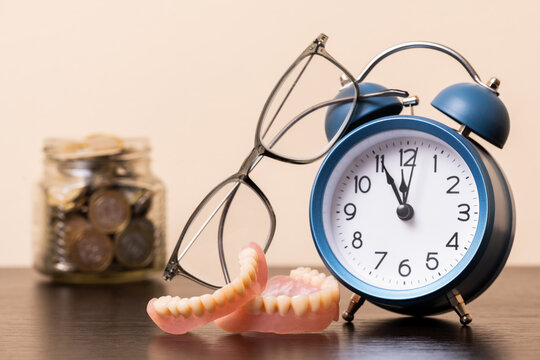 Alarm clock, reading glasses, dentures and a jar of coins