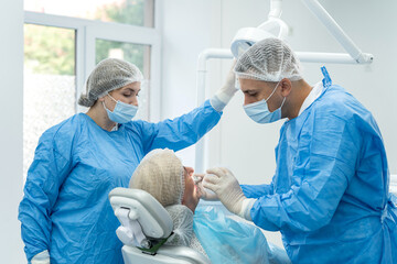 dentist-orthopedic doctor and his assistant examine a young retired woman at clinic