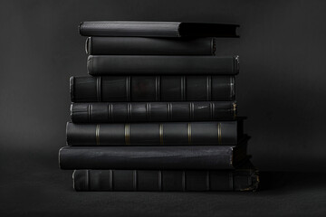 Stack of black hardcover books on dark background