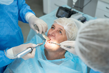 dentist surgeon installing an implant to an elderly woman. Prosthetic dentistry, false teeth