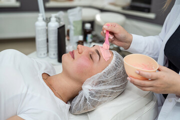 Young woman lying in spa and relax with with pink facial mask