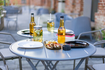 An outdoor restaurant table set with drinks, food, and plates, ready for dining. No people are...