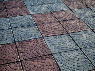 Abstract texture of a sidewalk lined with paving slabs with a rounded pattern. The seams between the paving slabs are located at an angle to the background.  Copy space.
