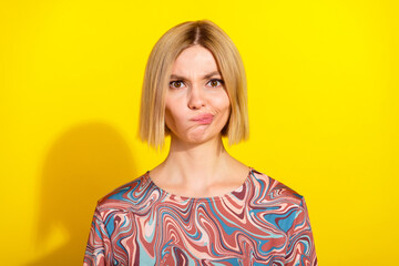 Cheerful young woman with blonde hair posing against a bright yellow background wearing a vibrant...