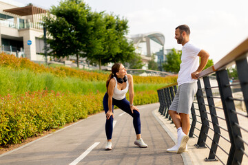 Engaging conversation between two fitness enthusiasts enjoying a sunny day in a beautiful urban park setting