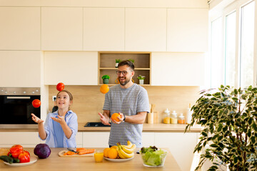 Enjoying a joyful moment in the kitchen while juggling colorful fruits during a family cooking session