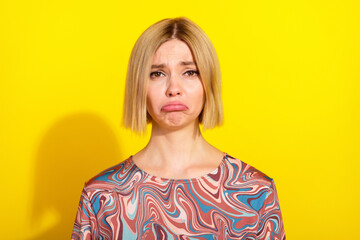 Young woman displaying a pouting expression in a bright yellow setting wearing a colorful patterned...