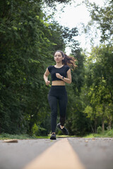 Portrait of Asian female runner jogging on street because jogging is a good exercise for good health. Beautiful Asian female runner is jogging on the street alone in morning for good health exercise.