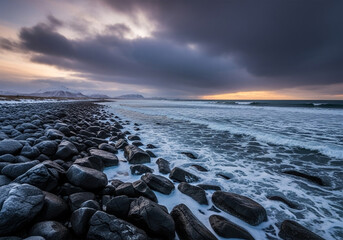A wide shot of a rocky winter beach at sunset