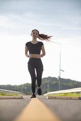 Portrait of Asian female runner jogging on street because jogging is a good exercise for good health. Beautiful Asian female runner is jogging on the street alone in morning for good health exercise.