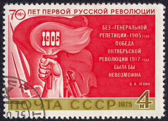 Hand holding a torch with fire on a red flag background. Postage stamp printed in the USSR in 1975, dedicated to the 70th Anniversary of 1905 russian revolution.