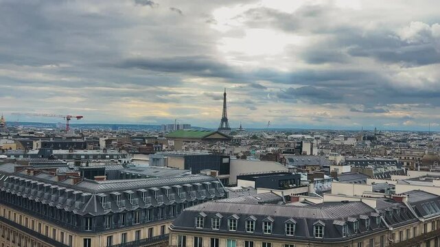 Panoramic top view of Paris, rooftops, Eiffel Tower and cloudy sky from the free observation deck on the roof of the Galeries Lafayette.
