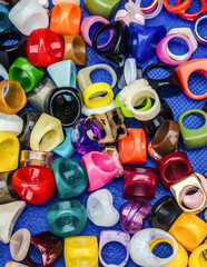 Colorful acrylic plastic rings in assorted shapes and styles on textured blue background. High...