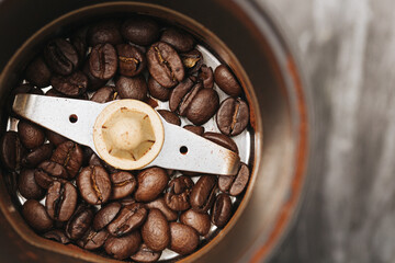 Top view electric coffee grinder with roasted beans. Open metal container full of brown coffee...