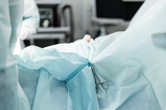 Surgical clamp secures sterile drape on operating table. Detail of preparation for laser therapy.