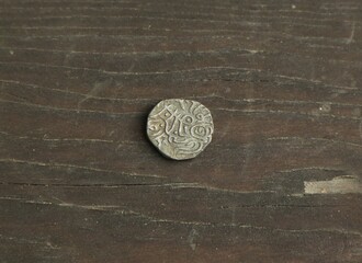Medieval silver coin of India on wooden table