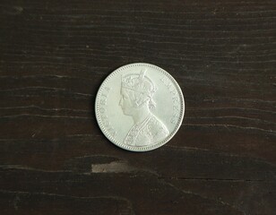 Old silver Indian coin one rupee on wooden table