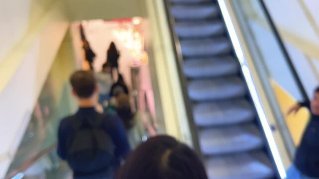 Descending on an escalator among a crowd of visitors to one of the floors of upmarket French department store Galeries Lafayette Haussmann in Paris, France. Out of focus.
