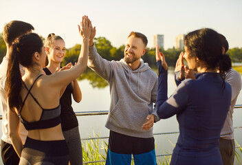 Victory gesture high five of two runners in honor of marathon achievement. Happy fit team of friends celebrate together end of sport challenge and teamwork in summer park. Healthy community concept
