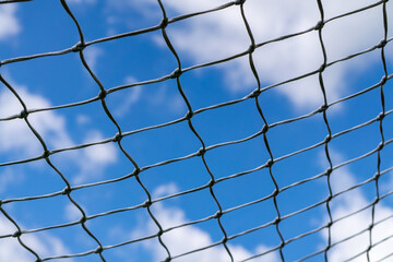 Goal net pattern against blue sky with clouds