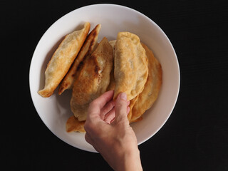 Hand take homemade fried empanadas.