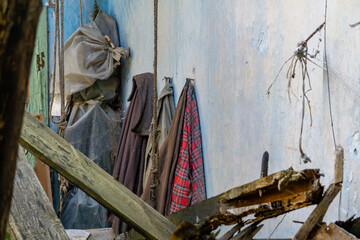 Ruined interior of an abandoned house with clothes hanging on a damaged wall – peeling paint,...