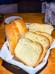 Sliced white bread in the busket onthe table.
