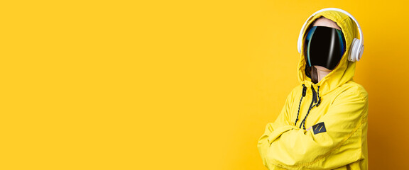 Young woman in cyberpunk glasses with headphones in a yellow jacket on a yellow background. Banner