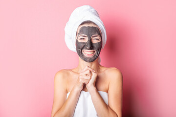 cheerful smiling young woman with black mask on her face on a pink background