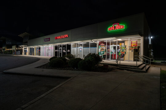 Papa Johns Pizza and SB Nails & Spa signs illuminated against dark sky, Bulverde, Texas