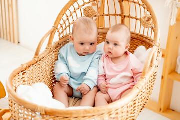 two babies, a boy and a girl in a wicker cot in the bedroom, a cute little baby of six months together, a place for text, newborn twins
