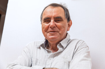 Elderly caucasian male smiling in light shirt against white background